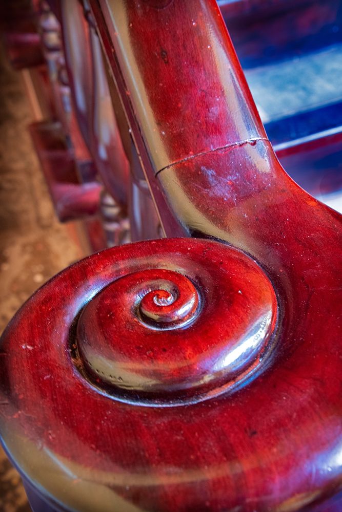 Snail shell-like curve on red wooden bannister handrail in Trinidad-Cuba